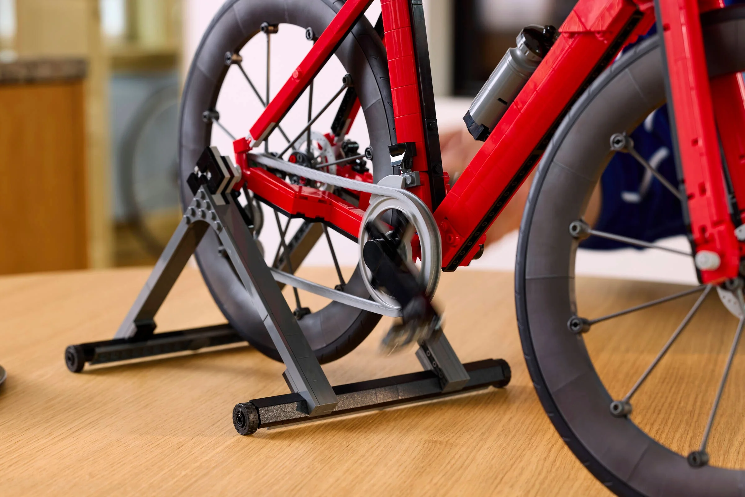 Prim plan al modelului LEGO Road Bike pe suport, cu detalii ale roților și lanțului vizibile.