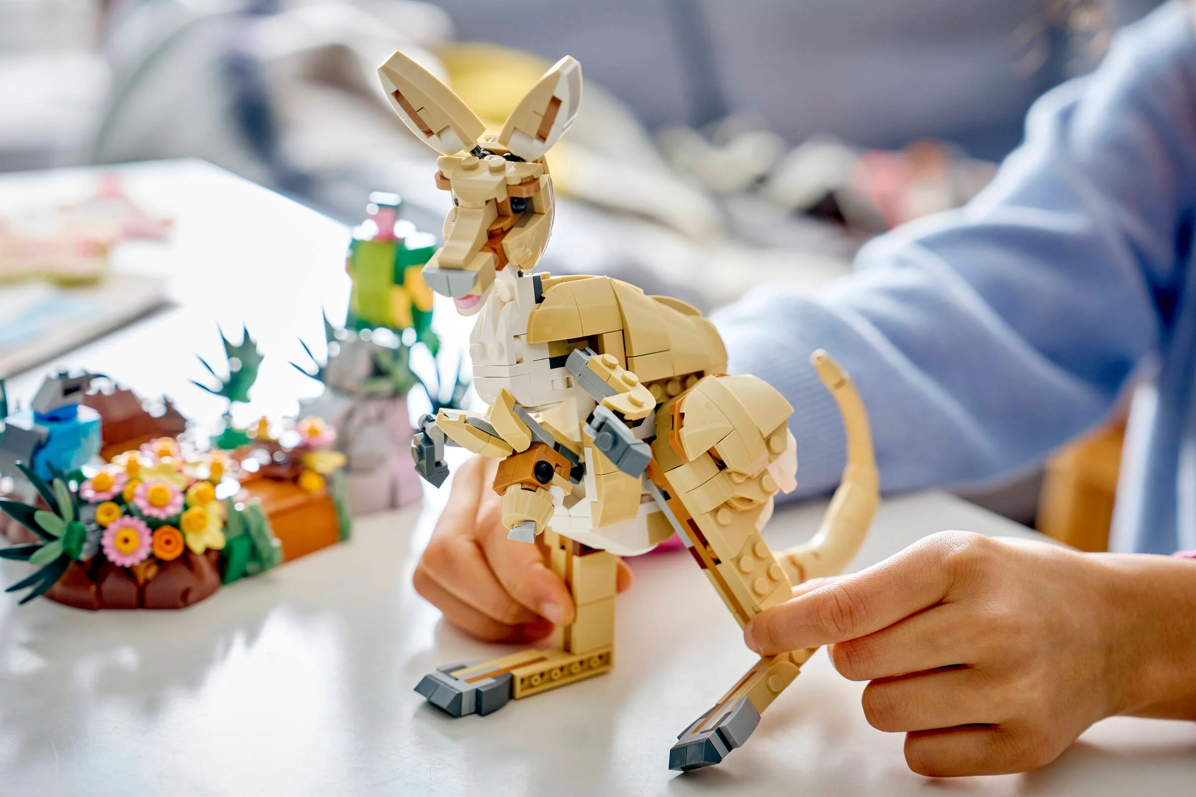 Koala LEGO construită, cu pui, ținută în mâini, detaliu fin al modelului.