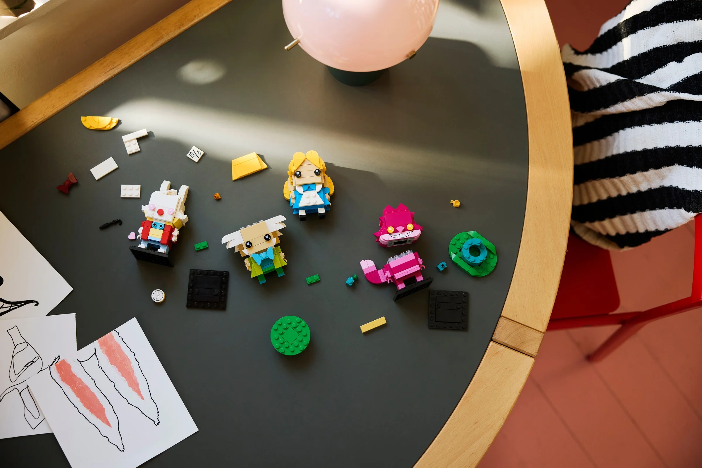 Imagine de ansamblu cu minifigurinele BrickHeadz Alice în Țara Minunilor și elemente de decor pe o masă.