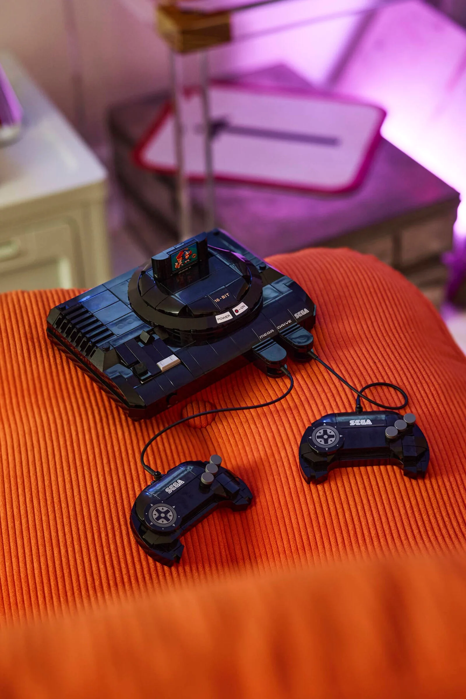 Consolă Sega Mega Drive construită din LEGO, cu două controllere și cartuș de joc.