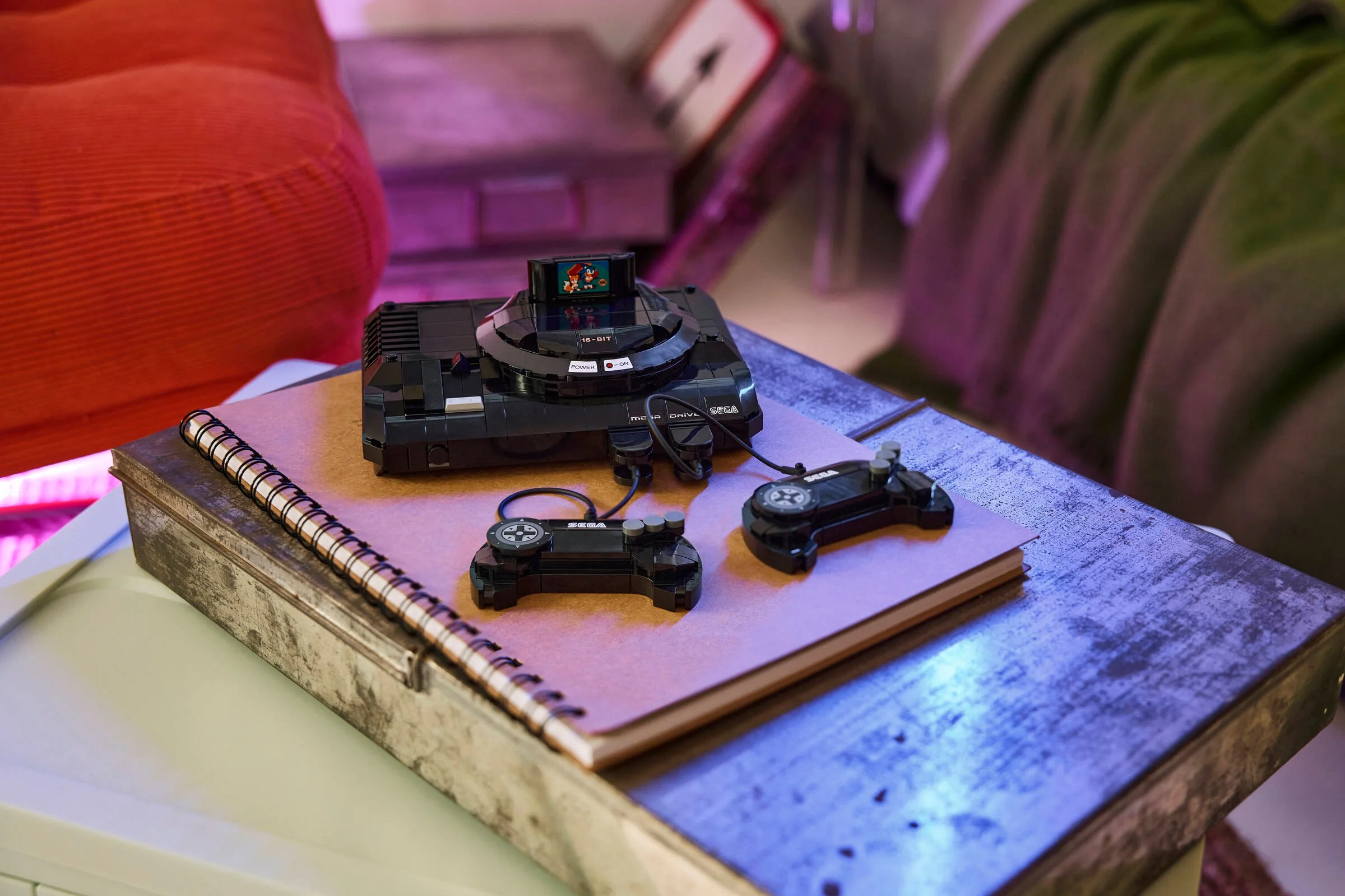 Consola SEGA Mega Drive LEGO, cu două controllere și cartuș de joc. O imagine detaliată.