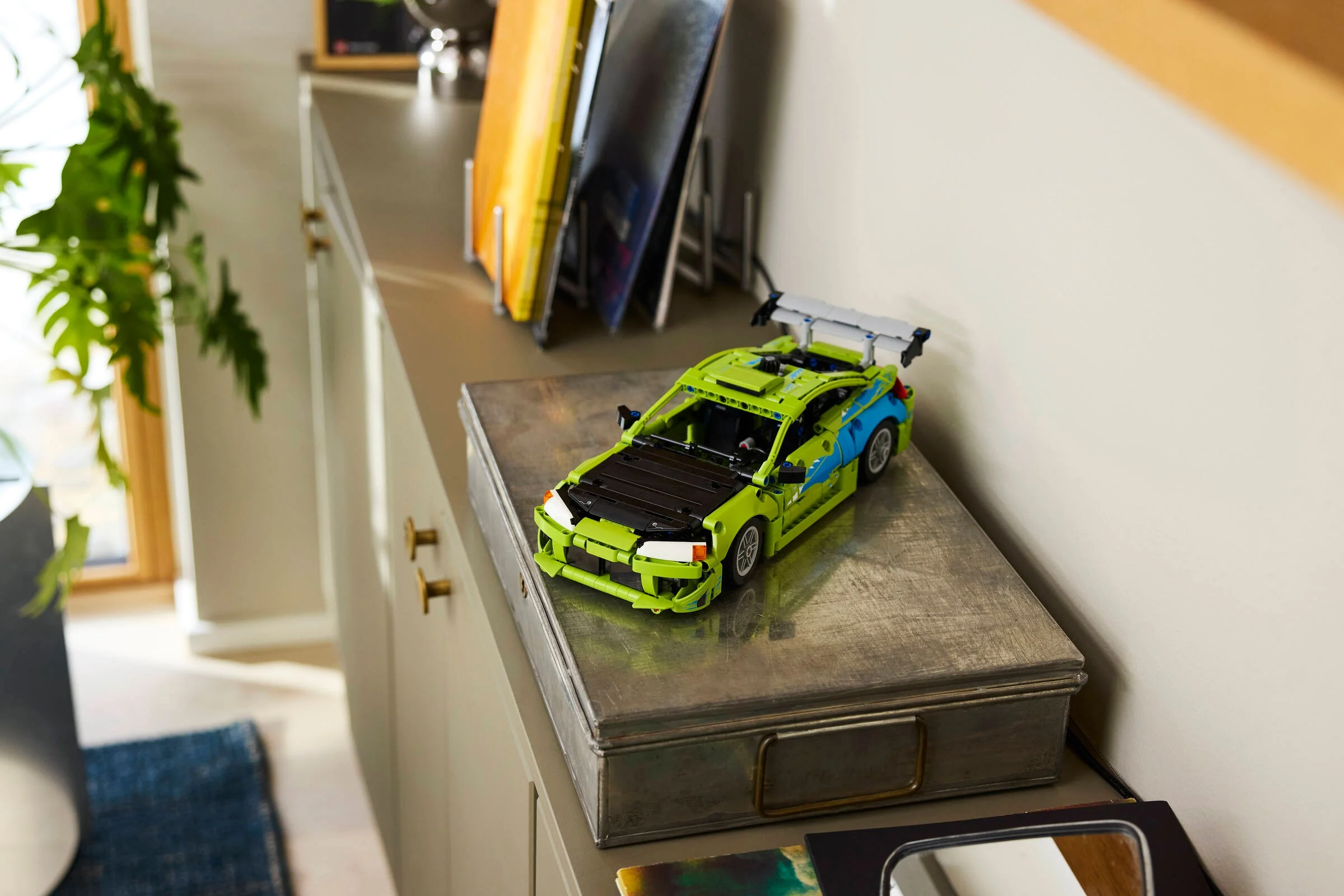 Modelul LEGO Mitsubishi Eclipse, verde și albastru, expus pe o cutie metalică într-o cameră modernă.