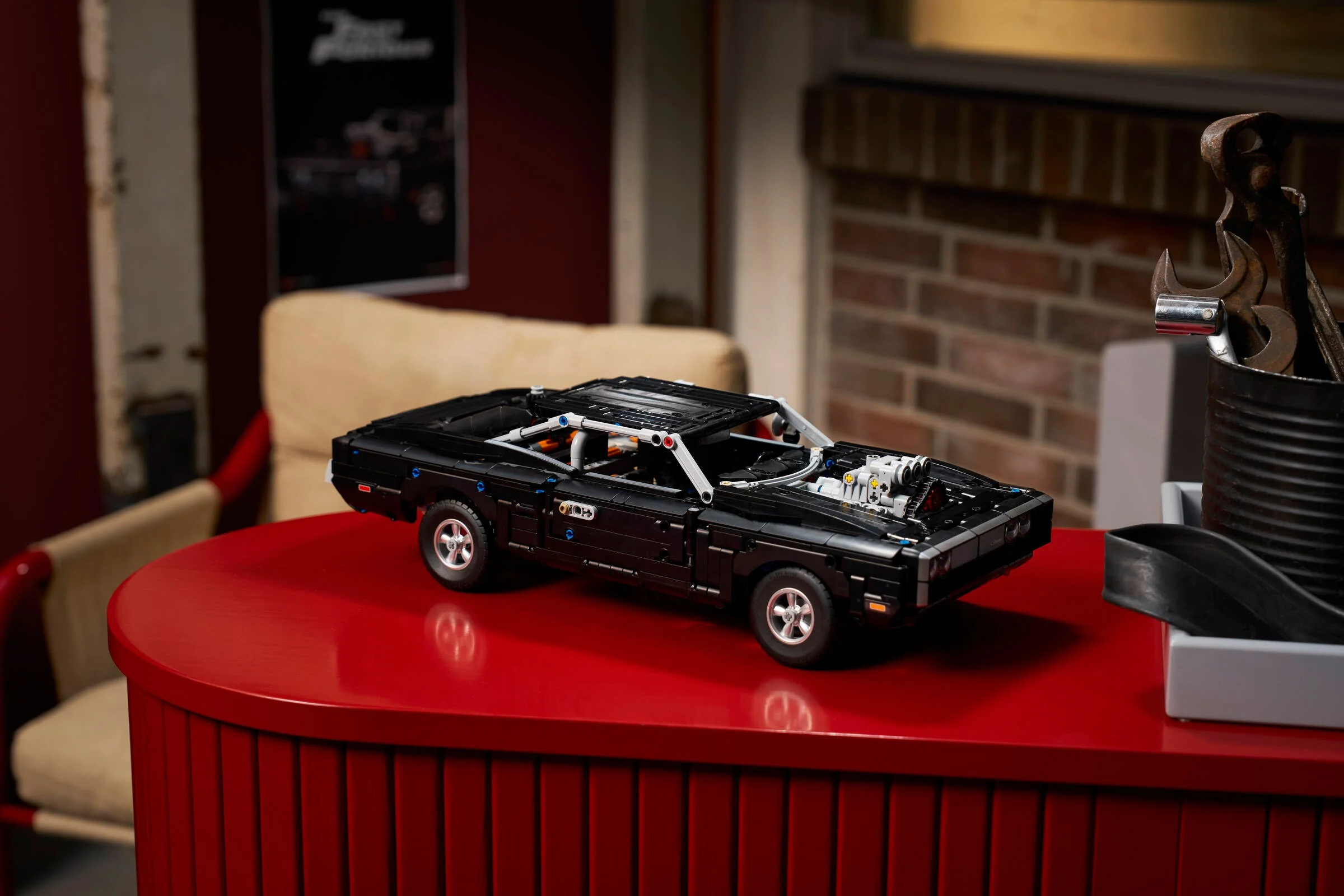 Modelul Dodge Charger R/T, detaliat și negru, pe o masă roșie într-un decor de garaj.