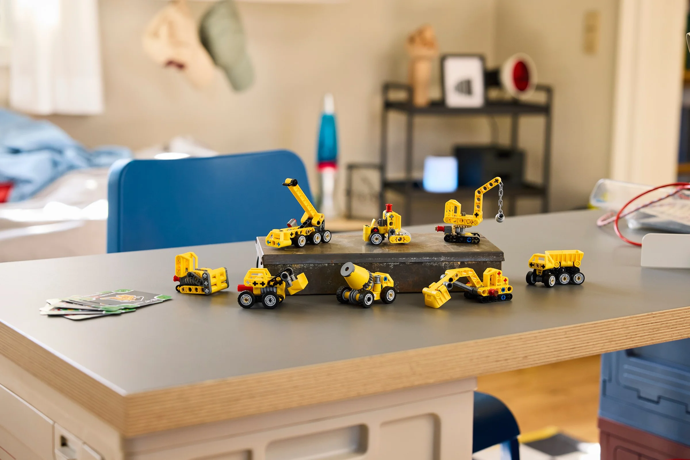 Imagine cu modelele LEGO Technic 42233 (Utilaje de Construcții) prezentate pe o masă, într-o cameră.