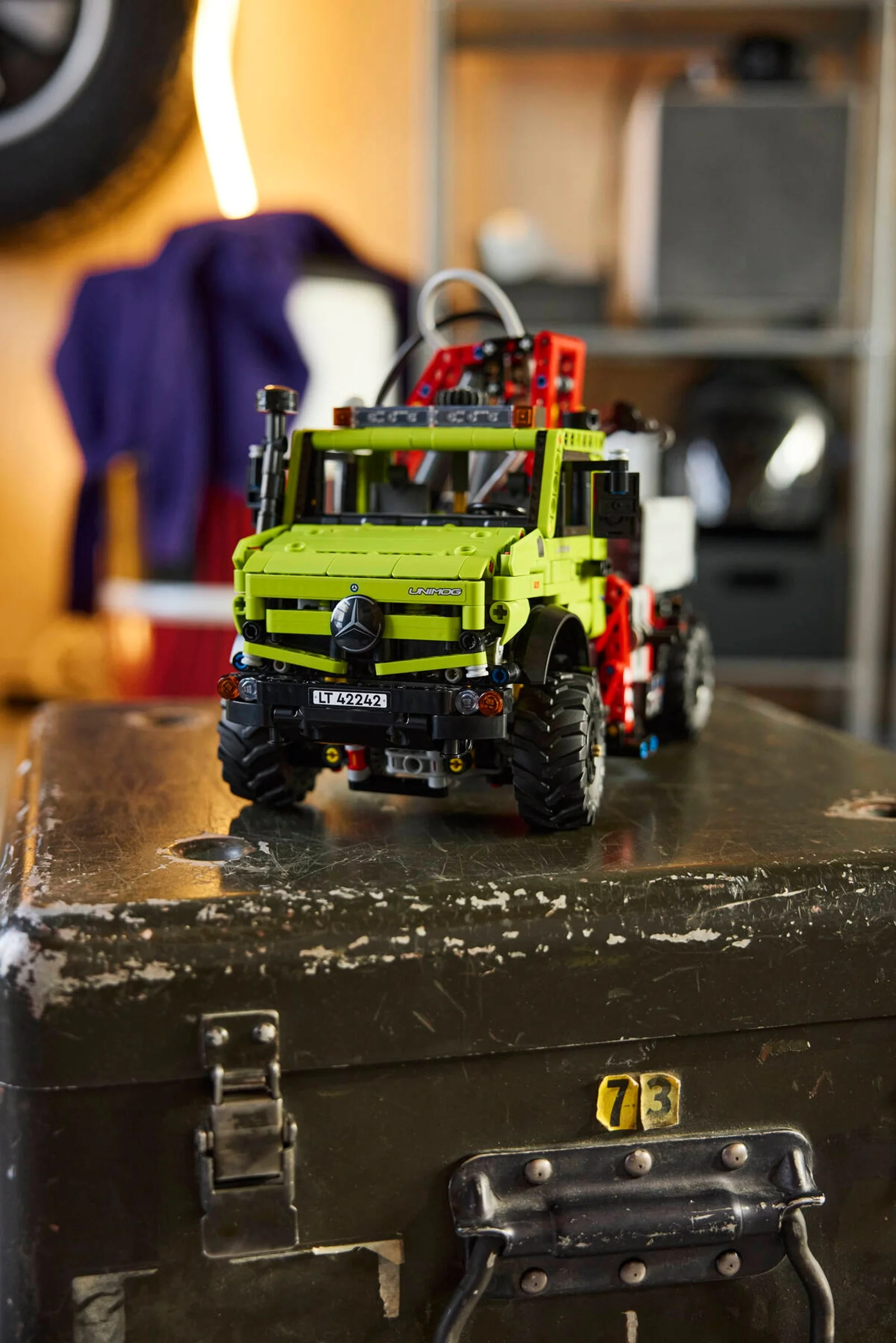 Unimog U 5023 cu macaraua, verde lime, pe o ladă metalică. Detaliu al modelului LEGO Technic.