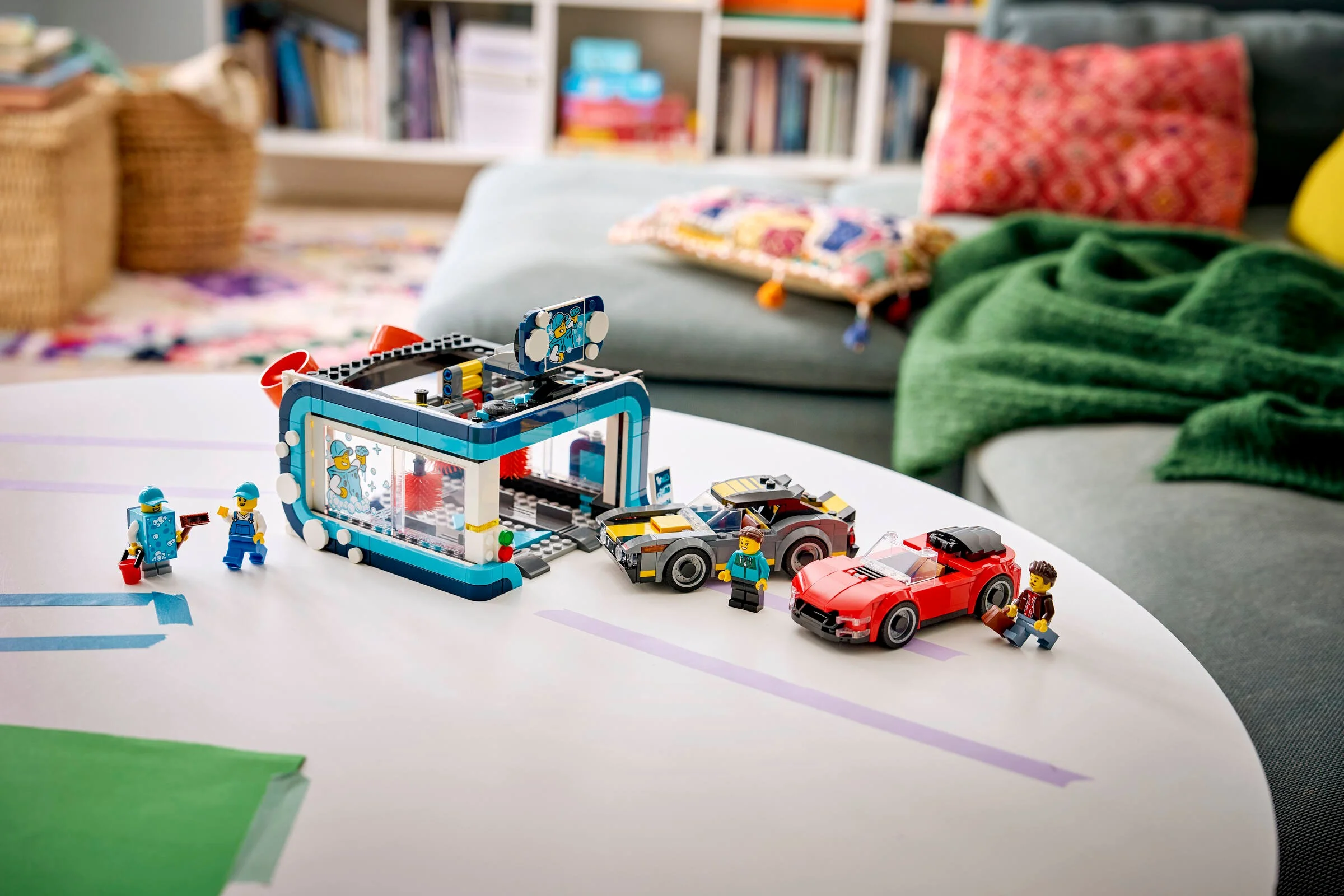 Setul LEGO 60497 Spălătorie Auto Drive-Through cu mașini și minifigurine, pozat pe o masă albă.
