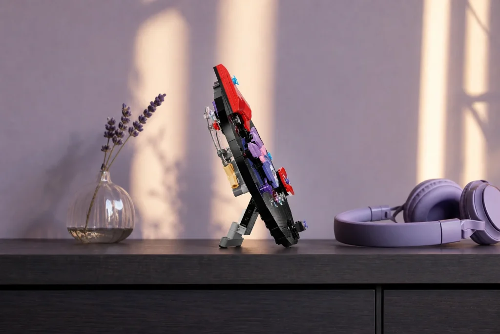 Setul LEGO 43028 Discul de vinil Olivia Rodrigo expus pe un cabinet de birou elegant, alături de o pereche de căști mov și o vază mică, în lumina caldă a apusului.