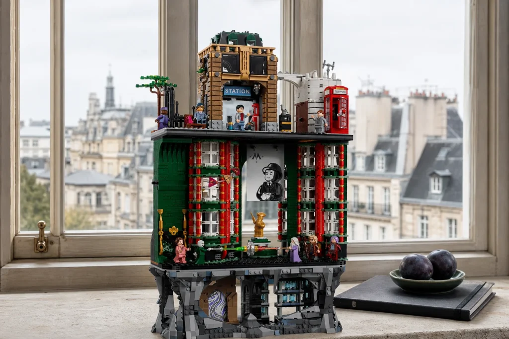 Setul LEGO Harry Potter Ministerul Magiei Ediție de colecție este expus pe un pervaz lat de piatră, sub lumina blândă a unei zile înnorate, alături de o schiță neagră și o farfurioară cu prune.